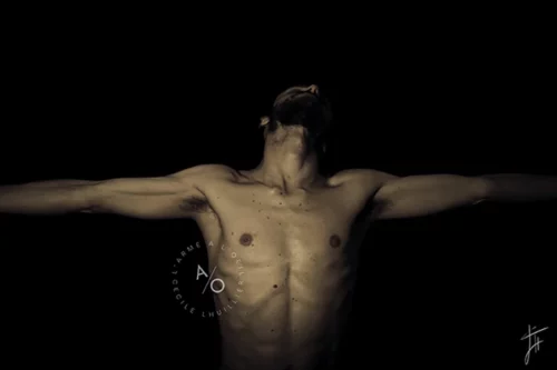 photo en studio d'un homme musclé, torse nu, bras en croix