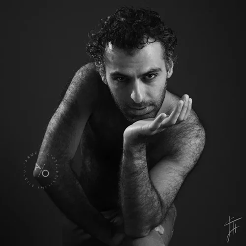 homme nu de face au regard pénétrant, menton posé sur sa main